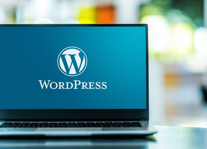 Notebook numa mesa com papel de parede do Wordpress