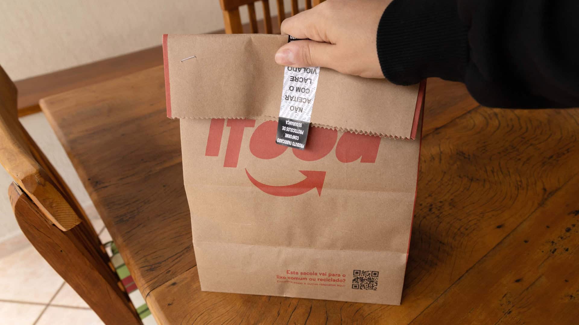 Pessoa segura sacola de comida entregue por restaurante parceiro do iFood