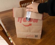 Pessoa segura sacola de comida entregue por restaurante parceiro do iFood