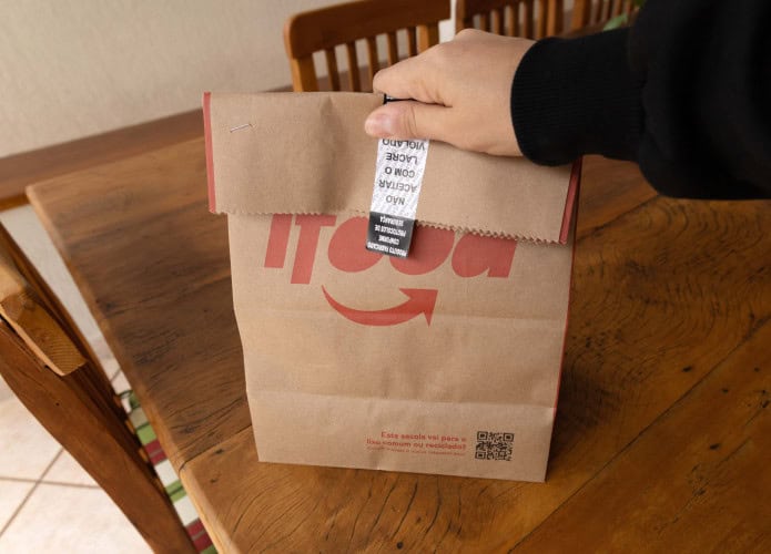Pessoa segura sacola de comida entregue por restaurante parceiro do iFood
