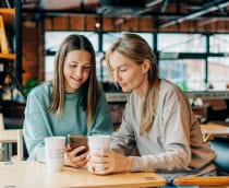 Duas mulheres na cafeteria olhando o celular