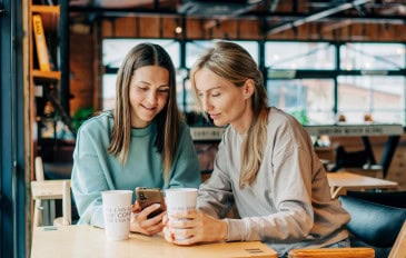Duas mulheres na cafeteria olhando o celular