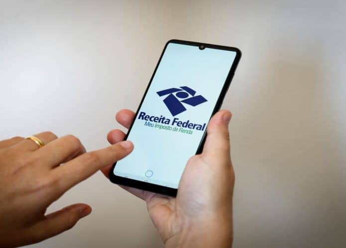 mãos com celular com aplicativo da Receita Federal aberto em