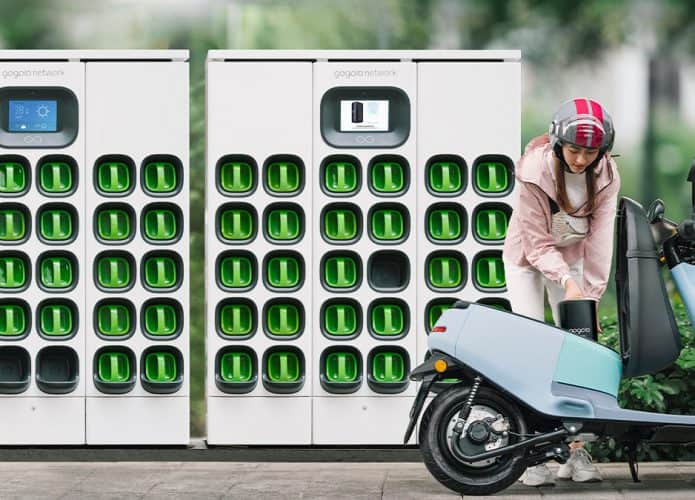 Mulher trocando bateria de scooter elétrica da Gogoro