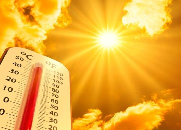 Termômetro gigante de temperatura com sol escaldante no fundo