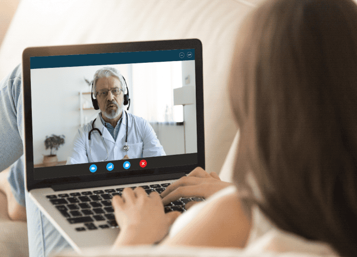Vista do monitor do PC sobre o ombro da menina, velho médico usa fone de ouvido uniforme dá consulta ao cliente via internet sobre surto epidêmico do vírus corona ncov, comunicação distante e conceito de proteção