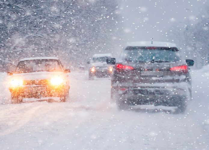Carros trafegando em rodovia coberta de neve