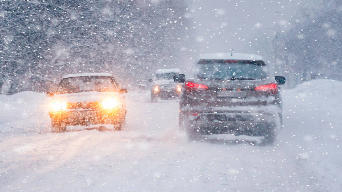 Carros trafegando em rodovia coberta de neve