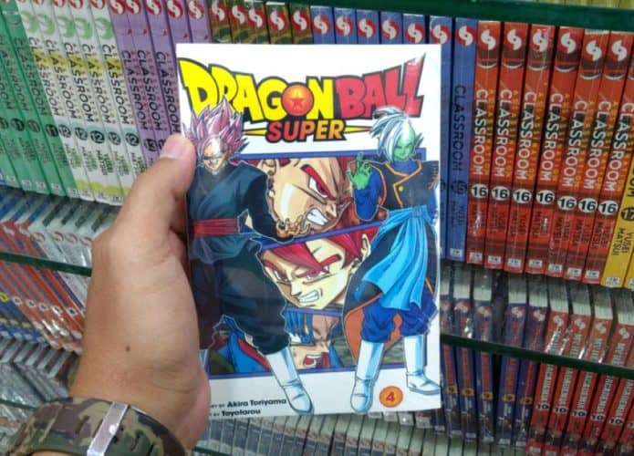 mão de home segurando uma revista de mangá com o título Dragon Ball Super