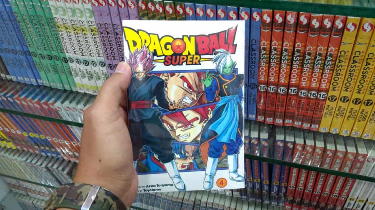 mão de home segurando uma revista de mangá com o título Dragon Ball Super