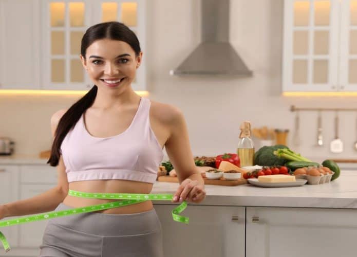 mulher com fita métrica na cintura e usando roupa de academia