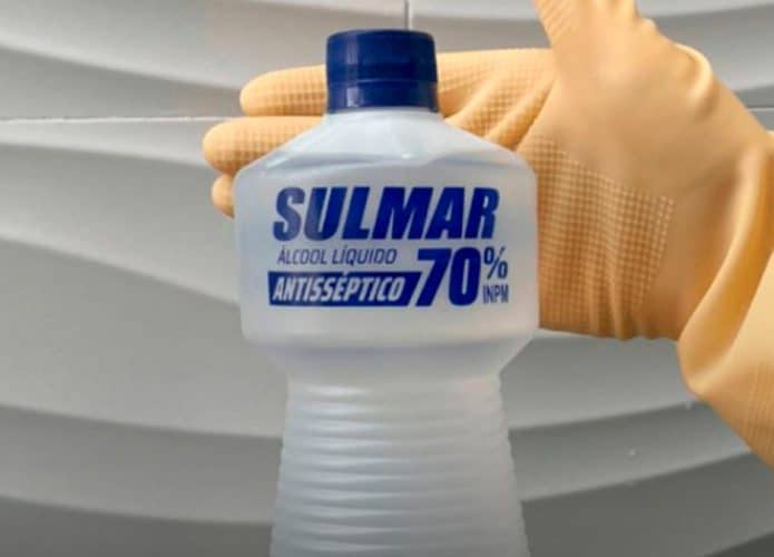 Pessoa com mão atrás de garrafa de álcool 70