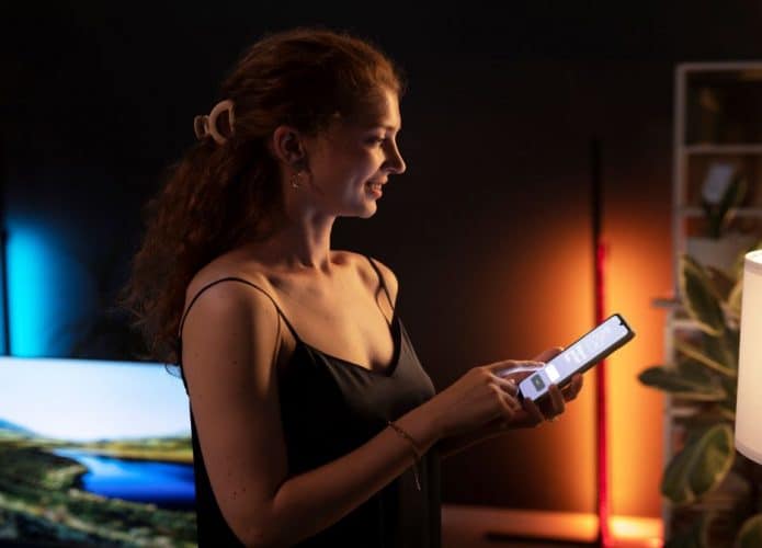 Mulher com celular controlando lâmpada inteligente