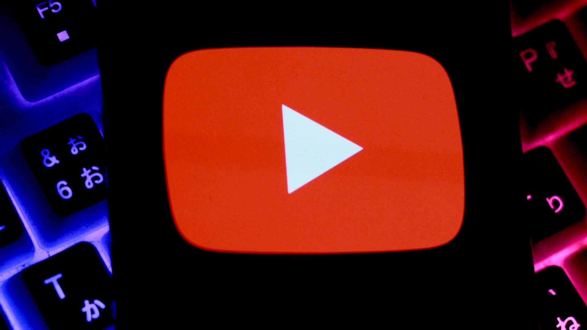 Celular com logotipo do YouTube na tela colocado sobre teclado mecânico gamer com luzes RGB acesas