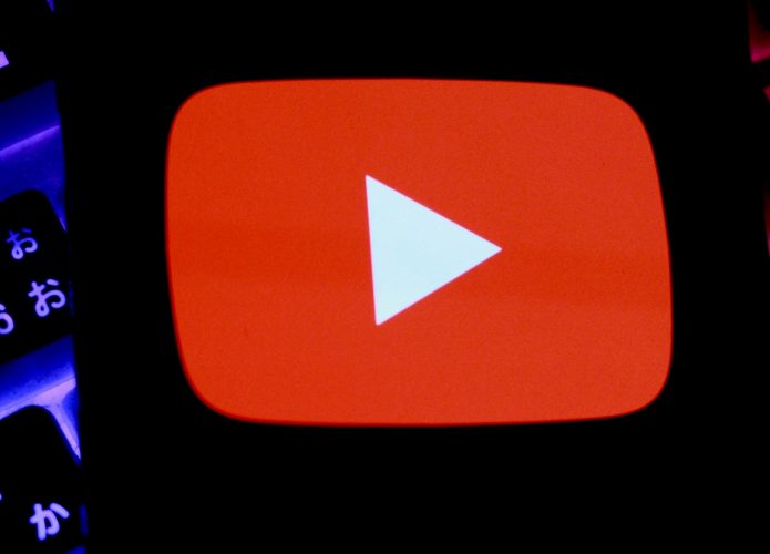 Celular com logotipo do YouTube na tela colocado sobre teclado mecânico gamer com luzes RGB acesas