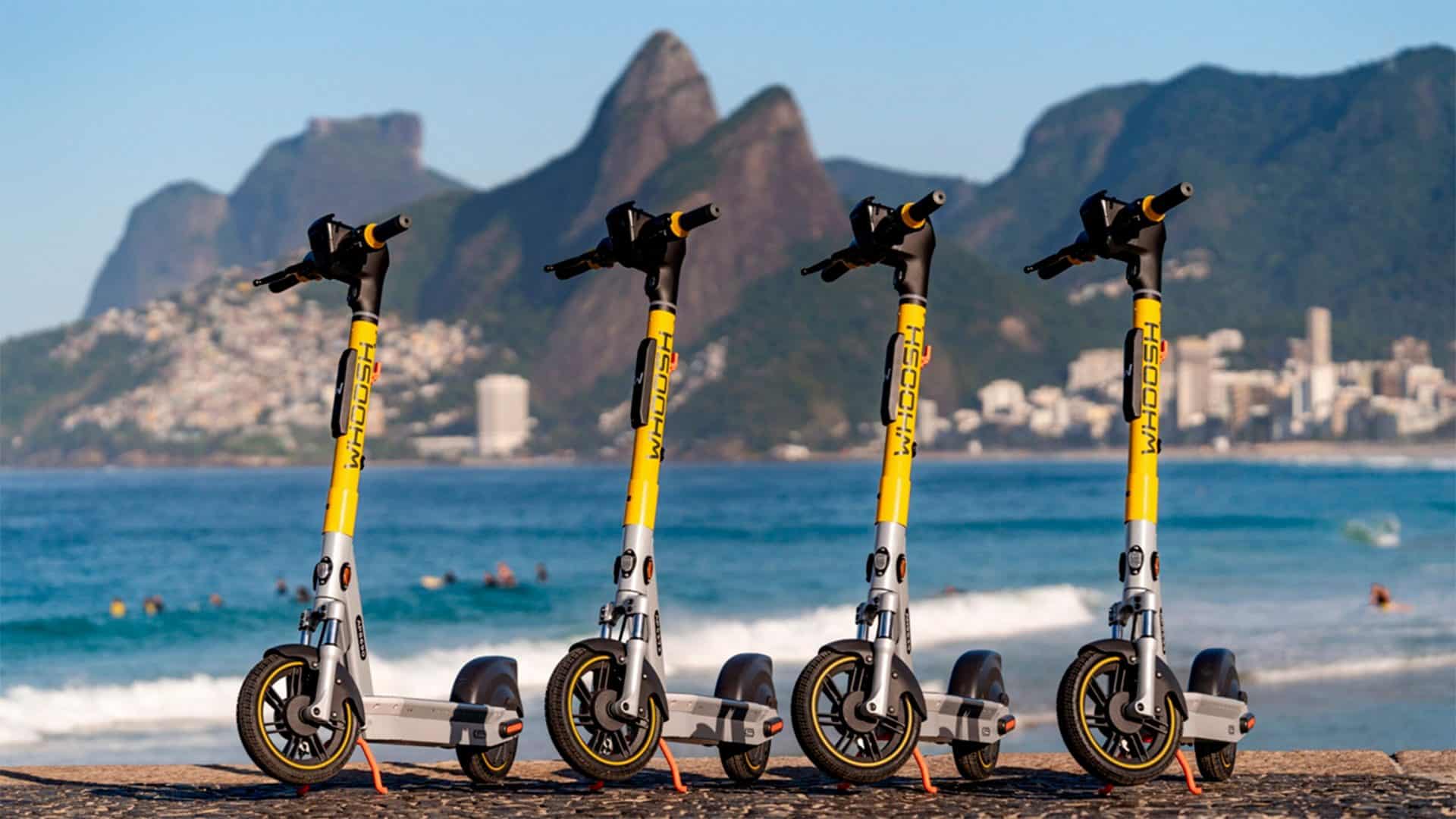 Patinetes elétricas da Whoosh enfileiradas em praia do Rio de Janeiro