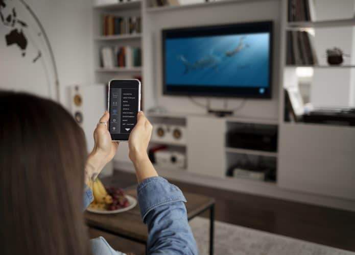 Apps para upnp e dlna - imagem de jovem usando celular como controle de TV