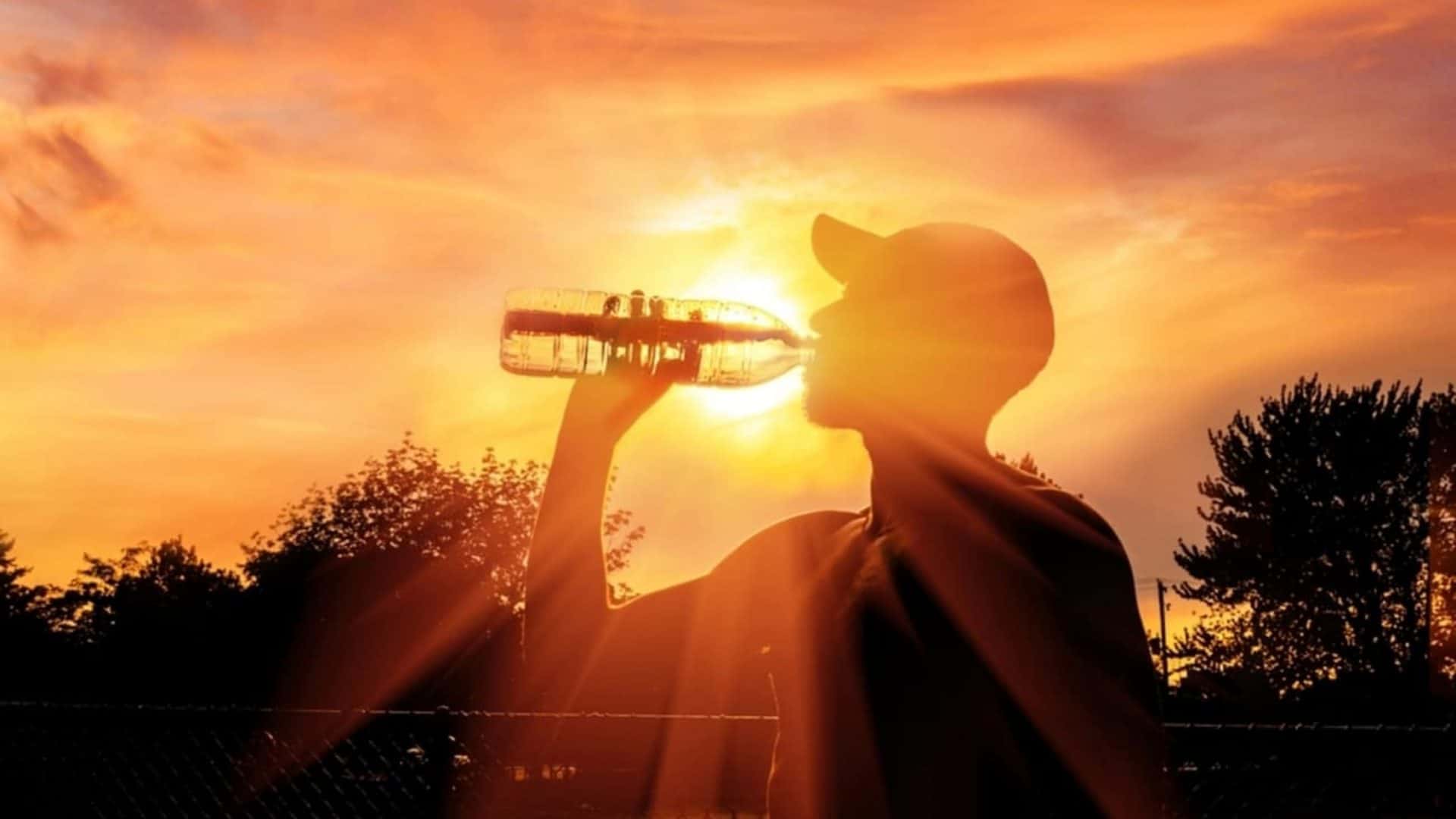 Sombra de uma pessoa levando uma garrafa de água à boca e tampando o Sol