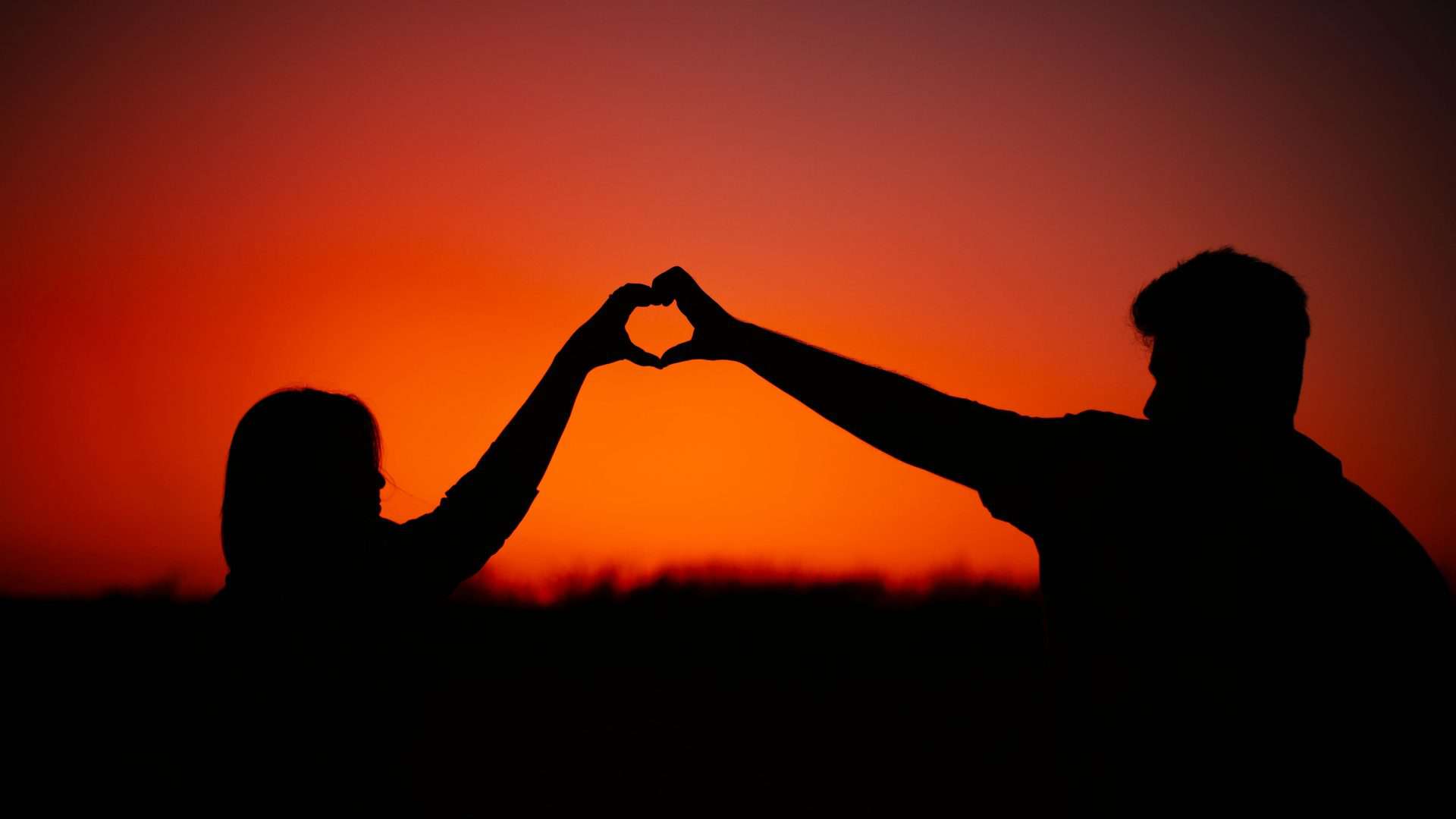 Cena de casal fazendo gesto de coração para ilustrar melhores filmes de romance