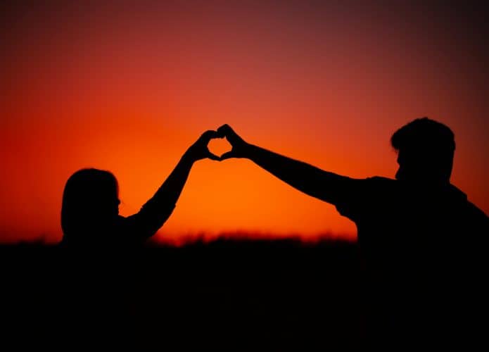 Cena de casal fazendo gesto de coração para ilustrar melhores filmes de romance