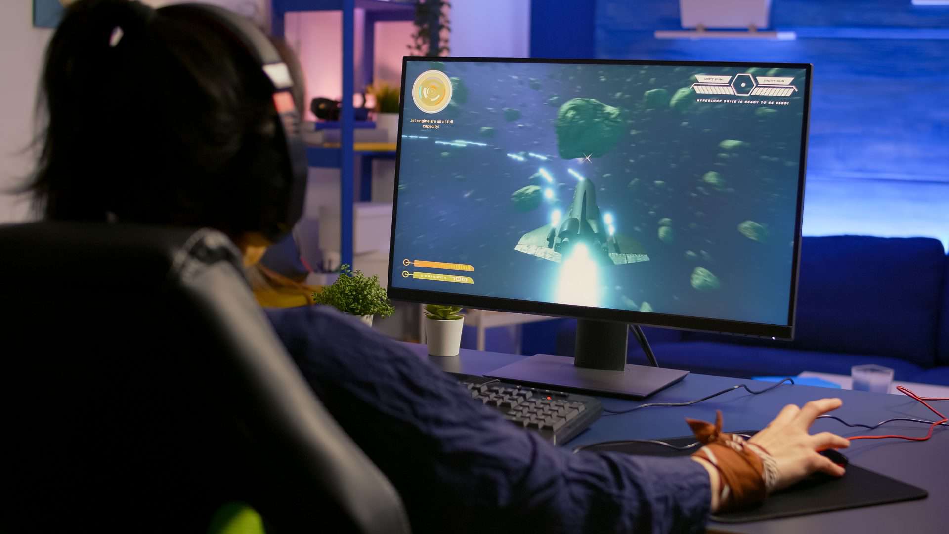 Pro winner gamer winning space shooter competition using professional RGB equipment. Player wearing headphone during virtual tournament late at night in gaming home studio