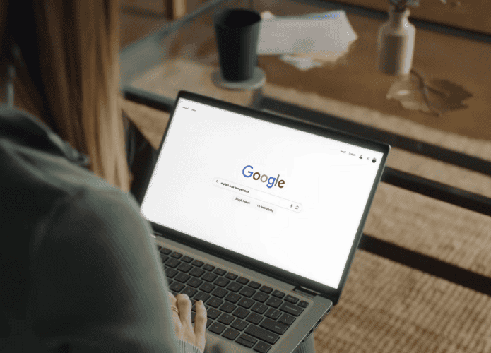 Mulher de costas realizando uma pesquisa no Google em um notebook