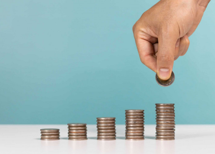 Pilhas de moedas e uma mão colocando outra em uma das pilhas