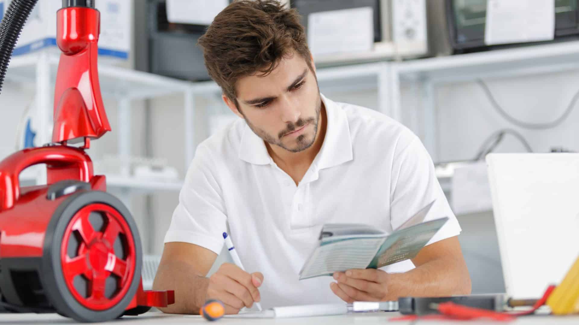 Imagem mostra homem lendo manual de instruções de um aspirador de pó