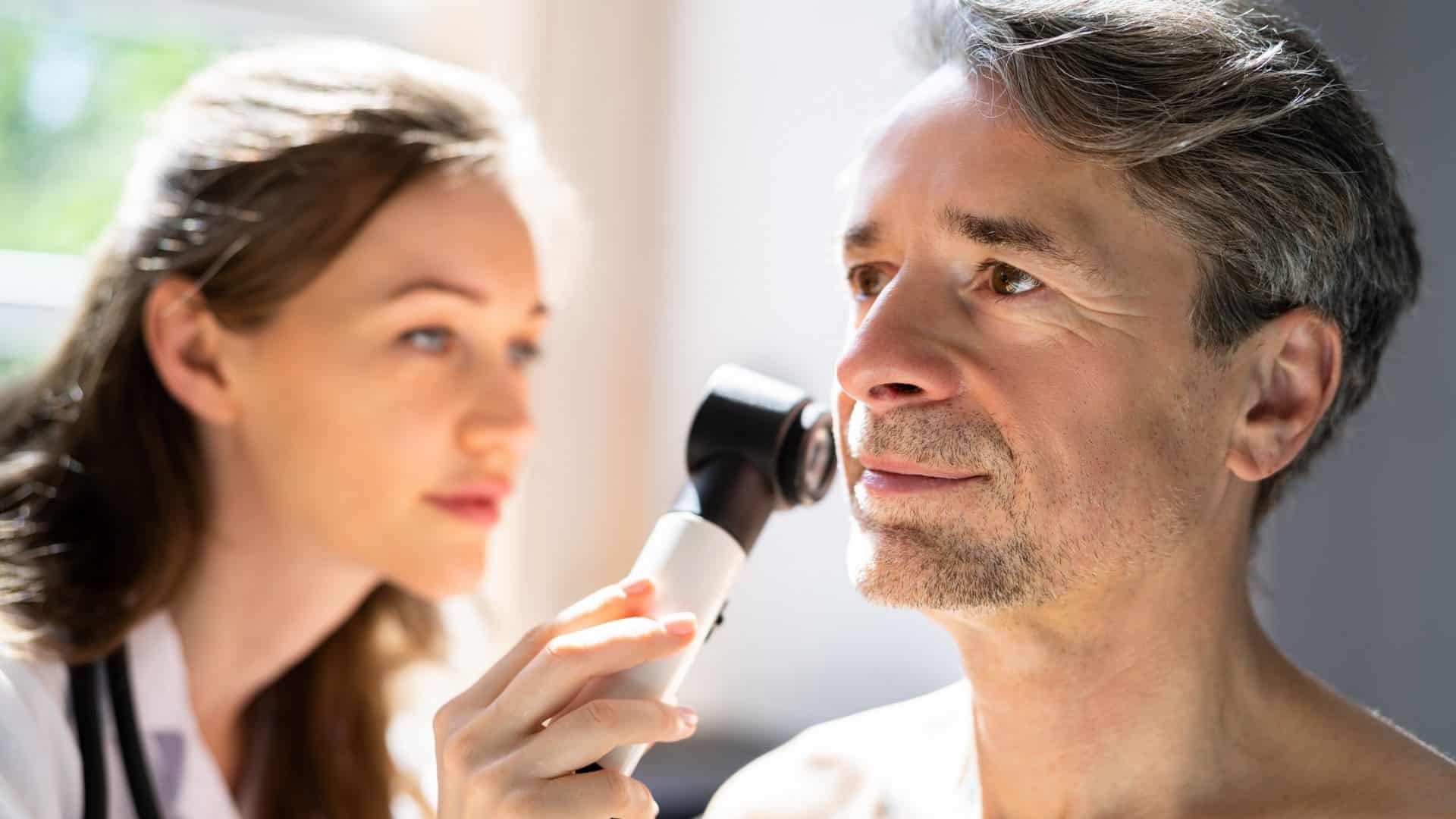 Médica avaliando pele de homem, dermatologista, consulta