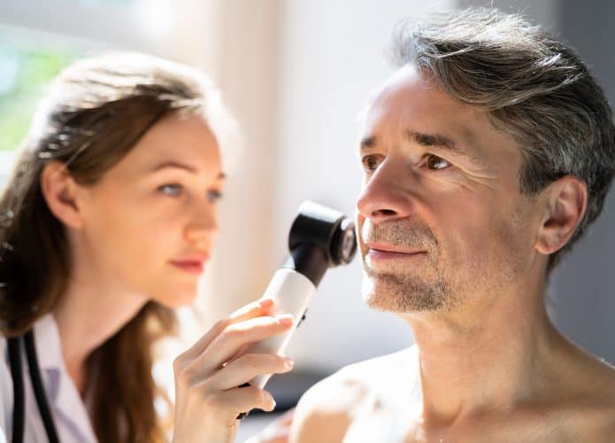 Médica avaliando pele de homem, dermatologista, consulta