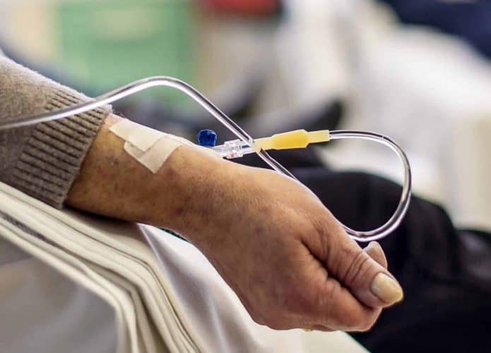 imagem mostra um paciente idoso num hospital, recebendo medicação direto na veia