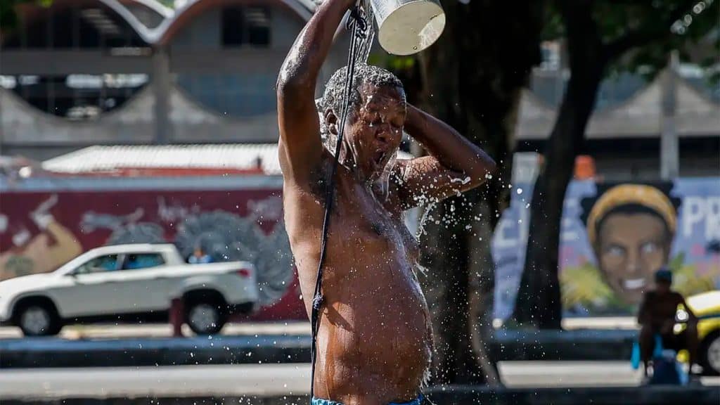 Homem jogando água sobre si mesmo em dia quente no Rio de Janeiro