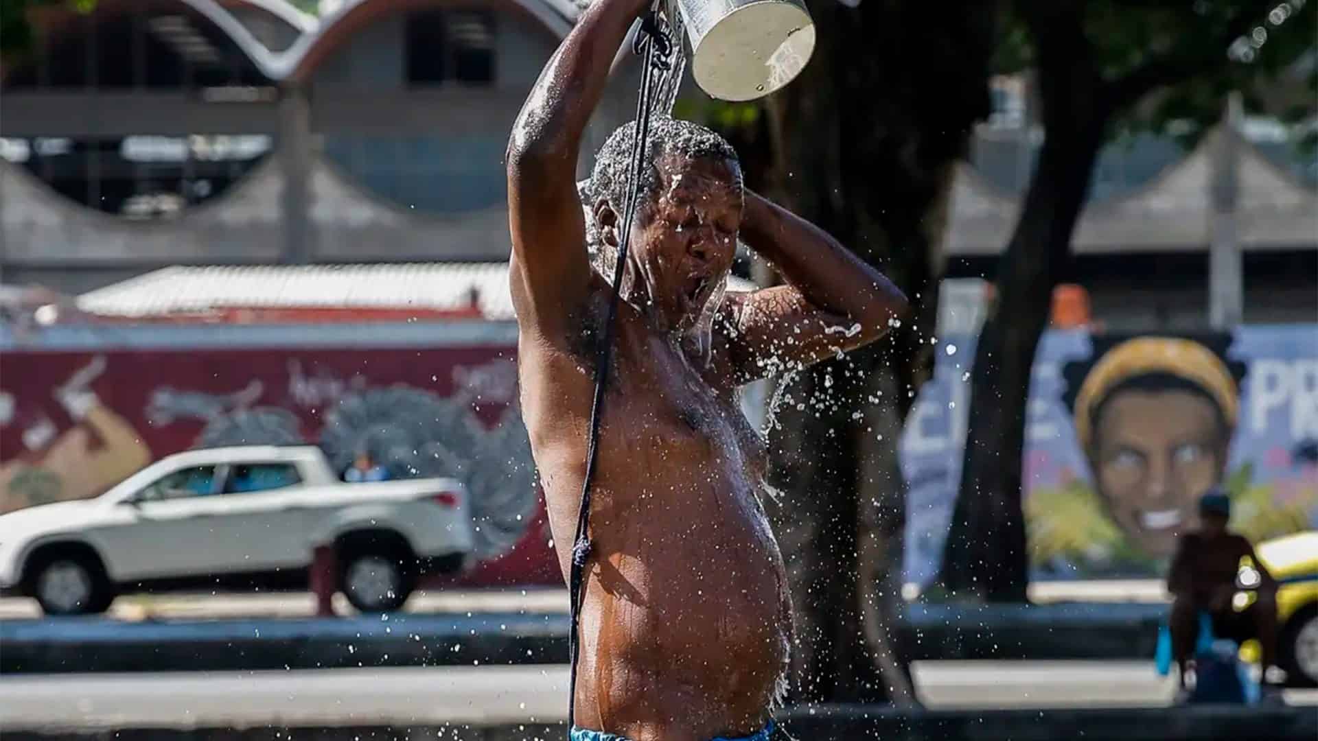 Homem jogando água sobre si mesmo em dia quente no Rio de Janeiro