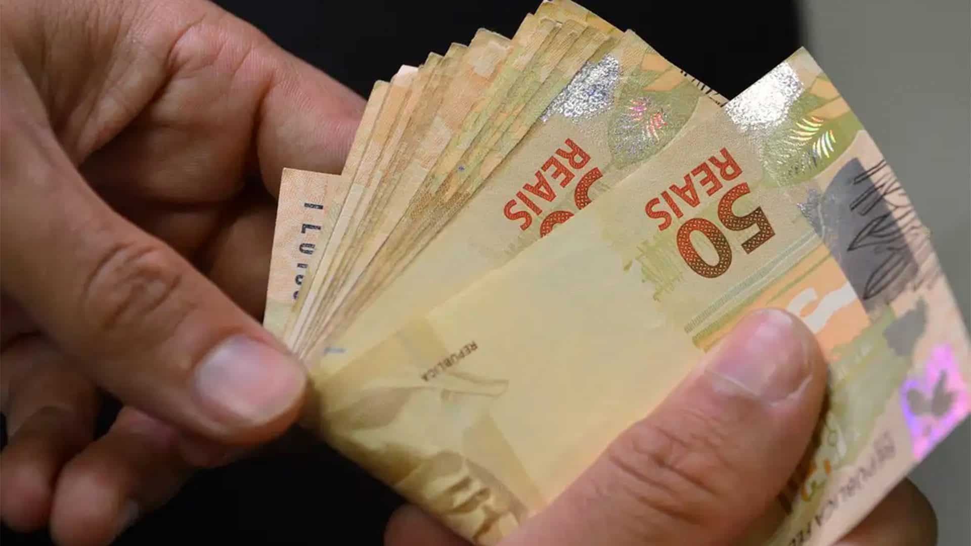 Homem contando notas de 50 reais