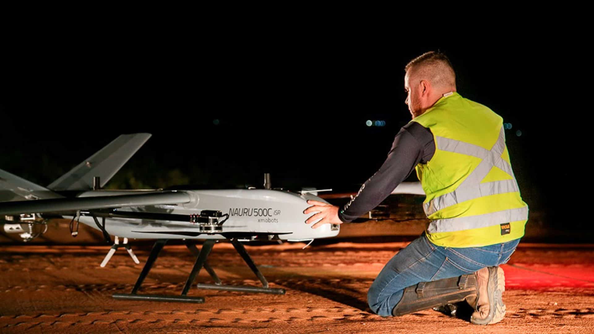 Homem agachado em frente drone Nauru 500C ISR, da Xmobots