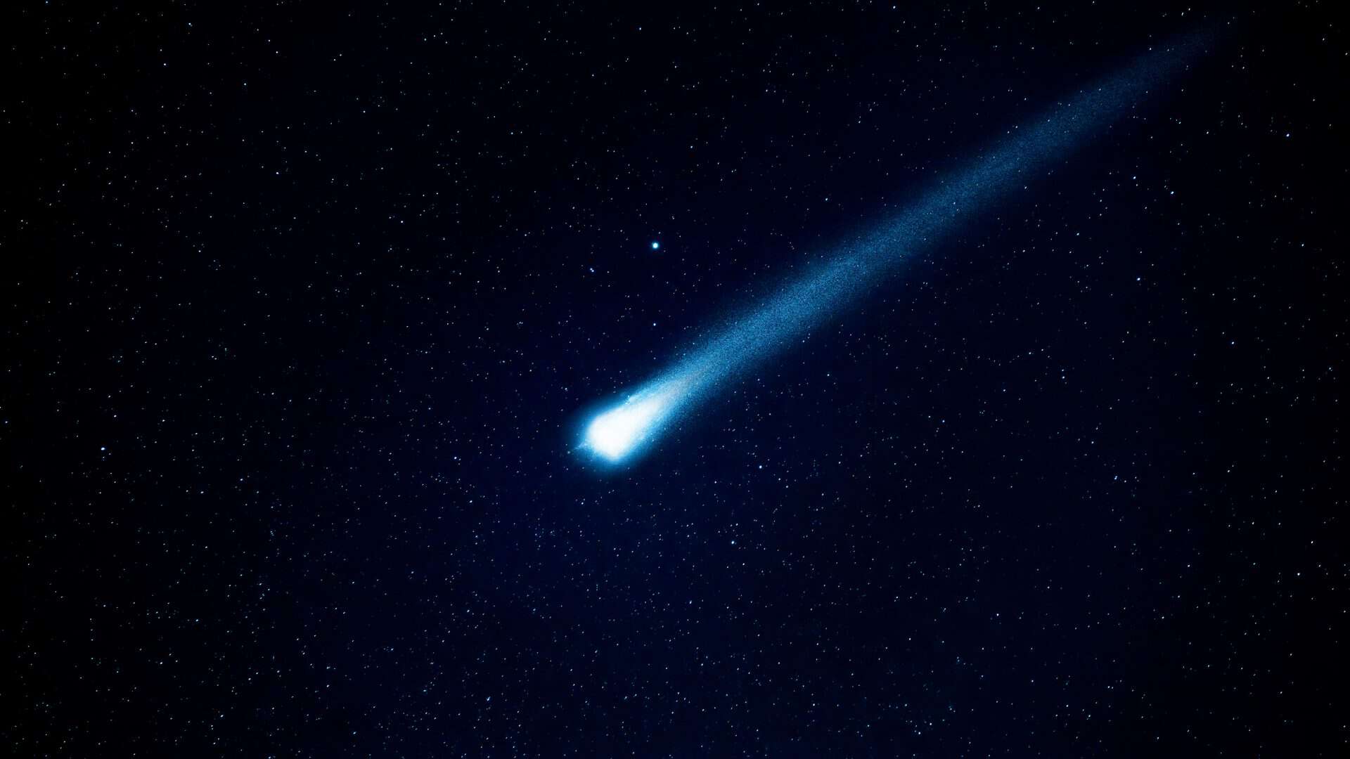 Meteoro com luz azulada rasgando céu estrelado