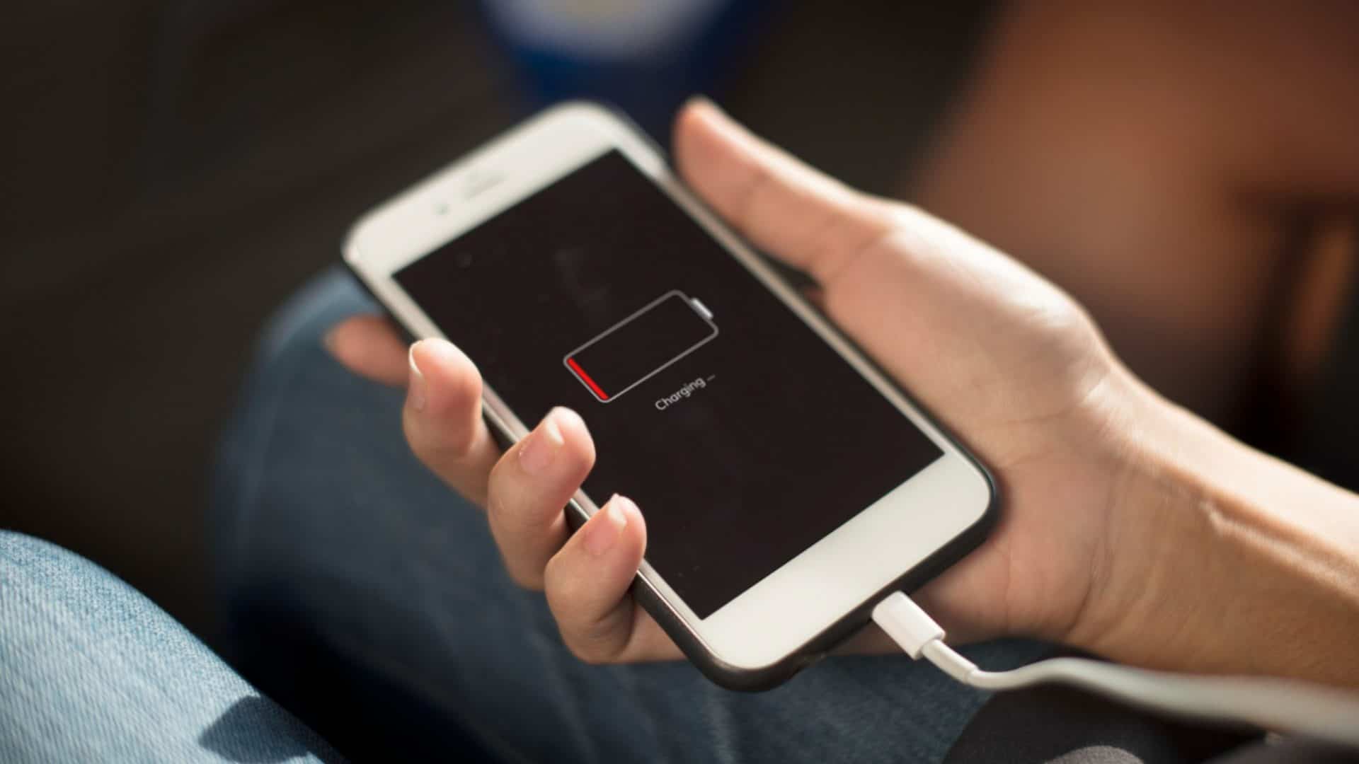 Celular carregando mostra display com carga baixa na mão de usuário