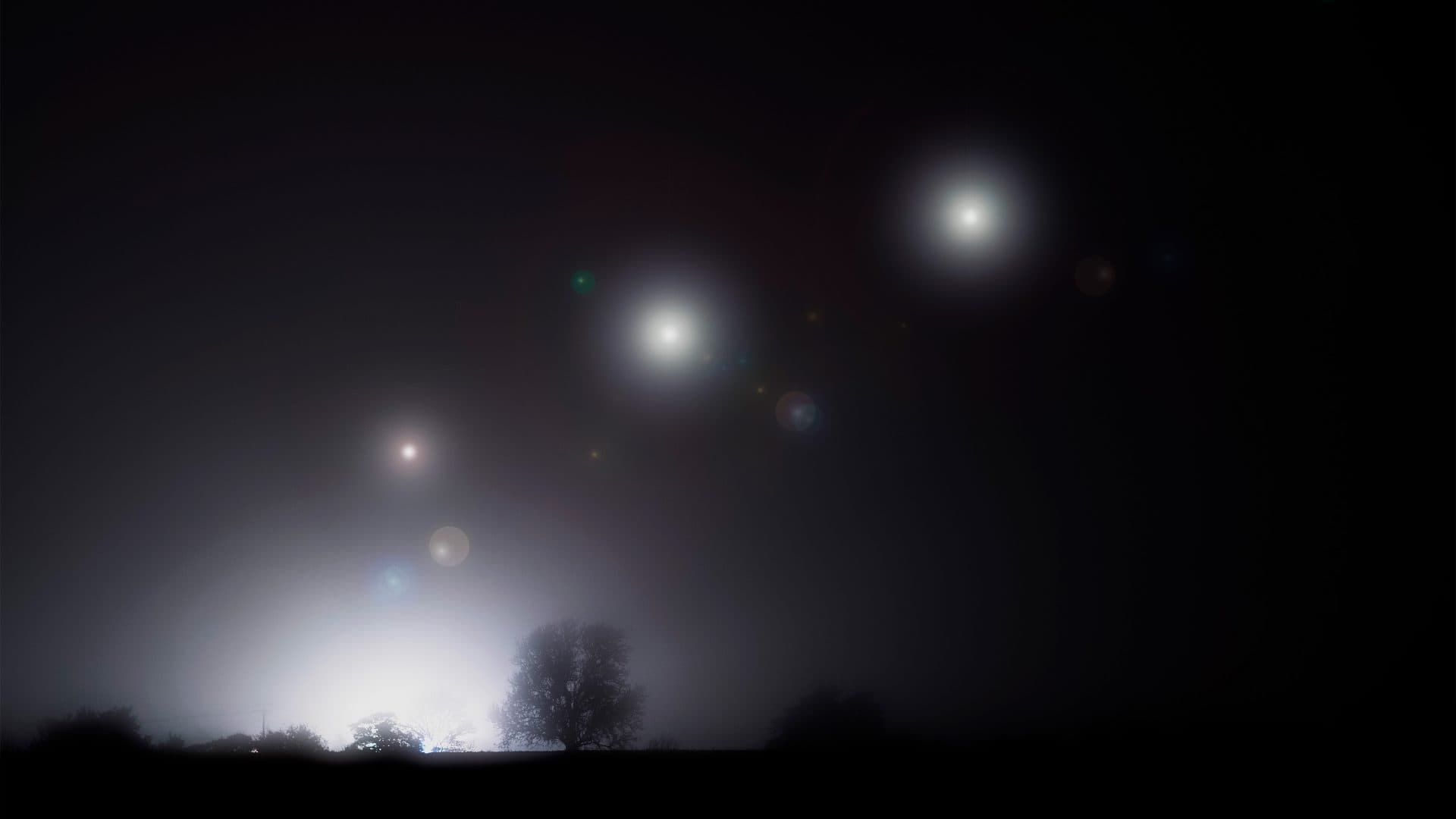 Luzes de óvnis em céu noturno com neblina em área rural