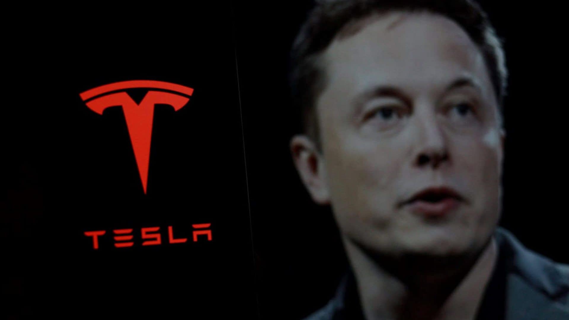 Elon Musk ao lado do logo da Tesla