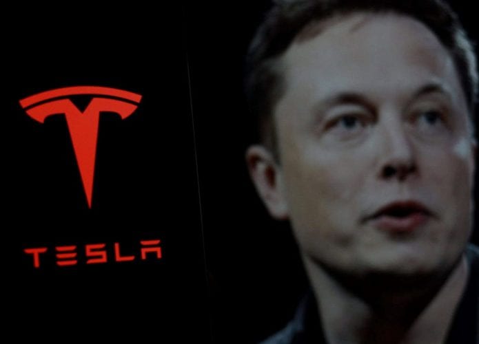 Elon Musk ao lado do logo da Tesla