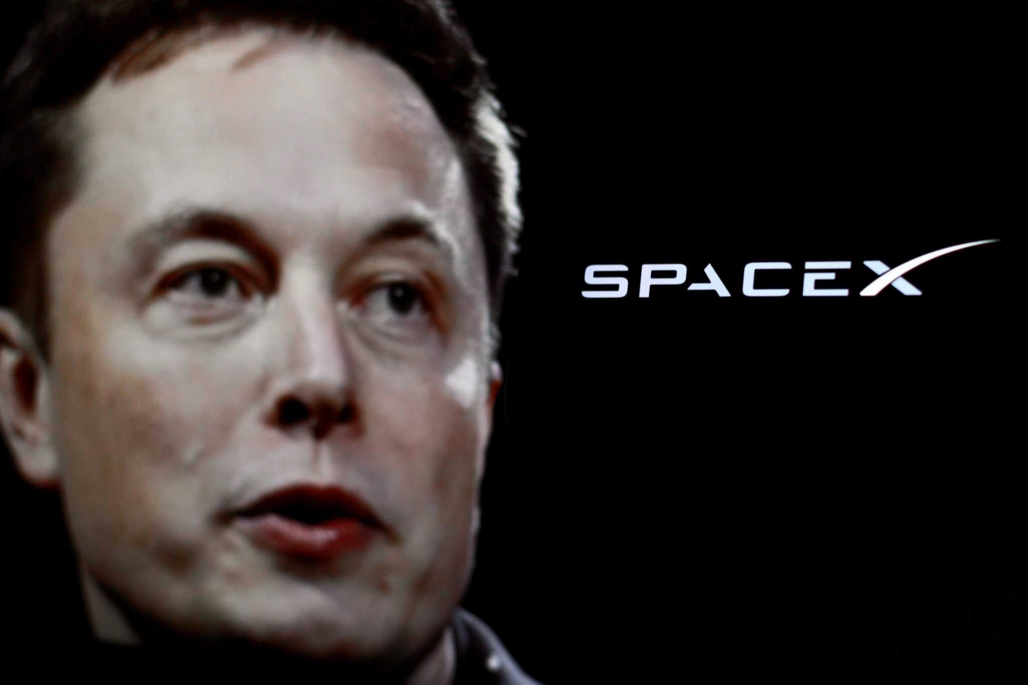 Elon Musk ao lado do logo da SpaceX