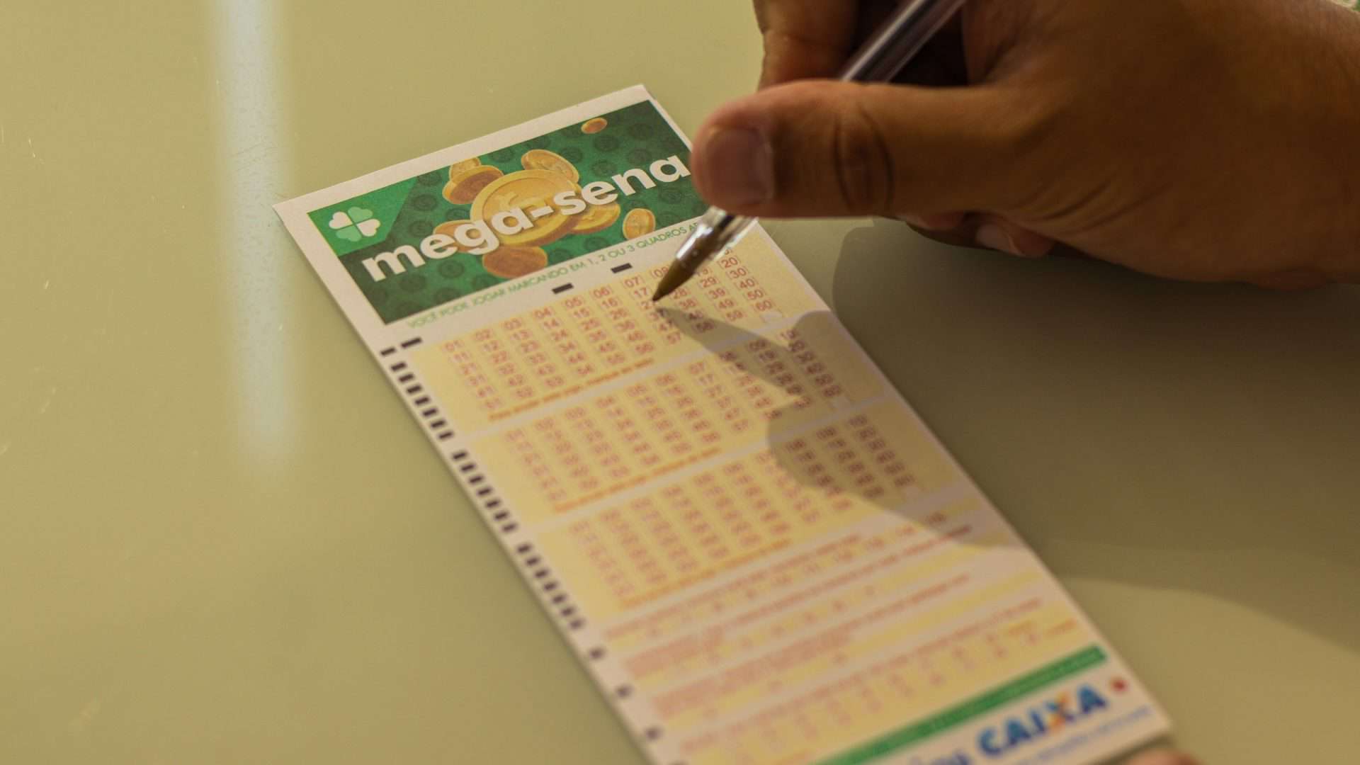 Pessoa preenchendo, com uma caneta, um jogo da Mega-Sena