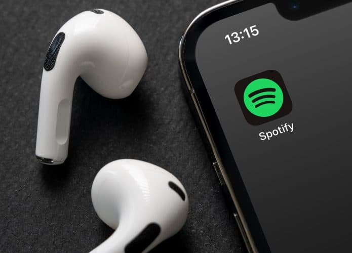 Fone de ouvido ao lado de um smartphone com o logo do Spotify