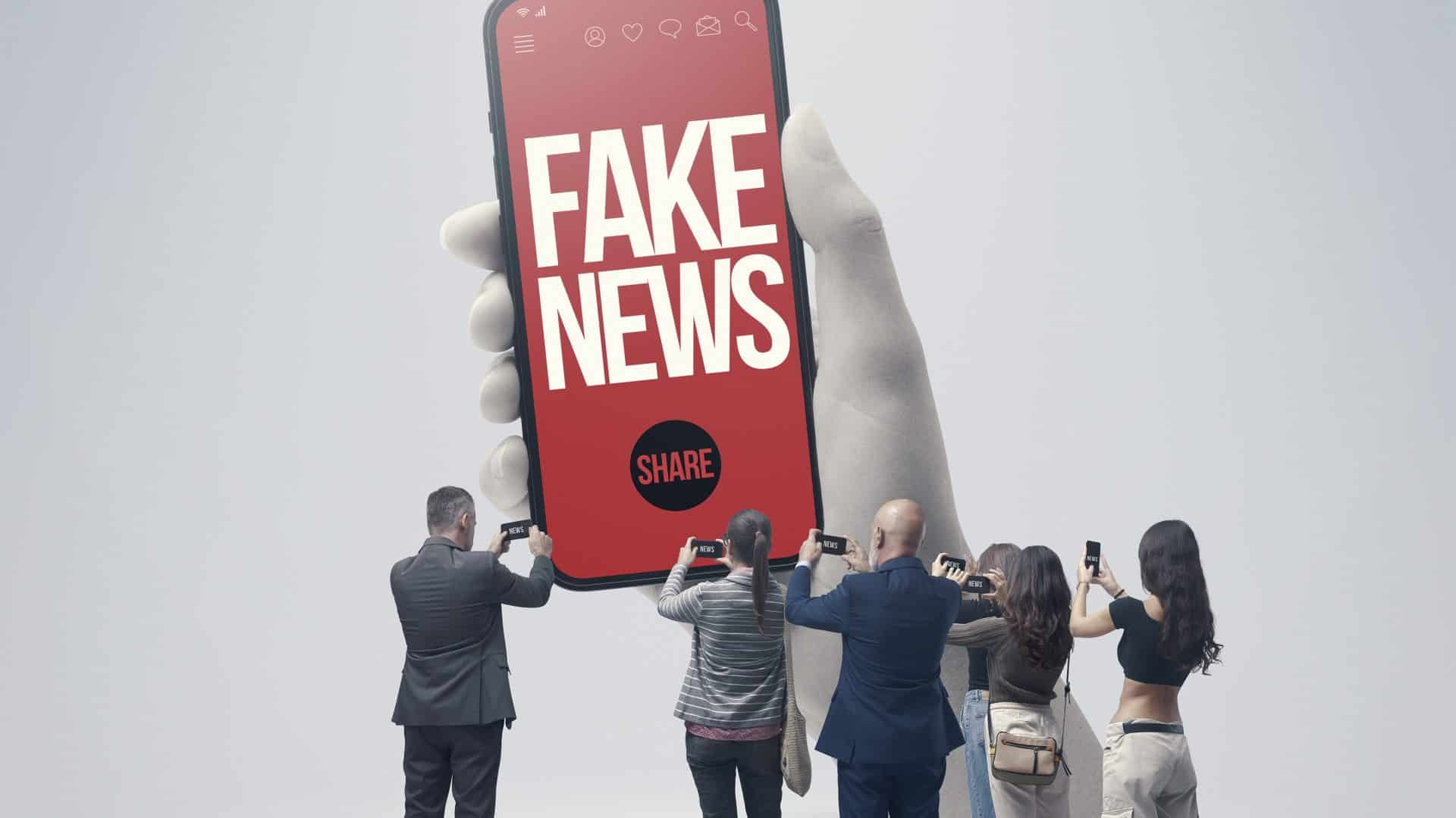 Ilustração de pessoas apontando celulares para mão gigante segurando celular com fake news na tela