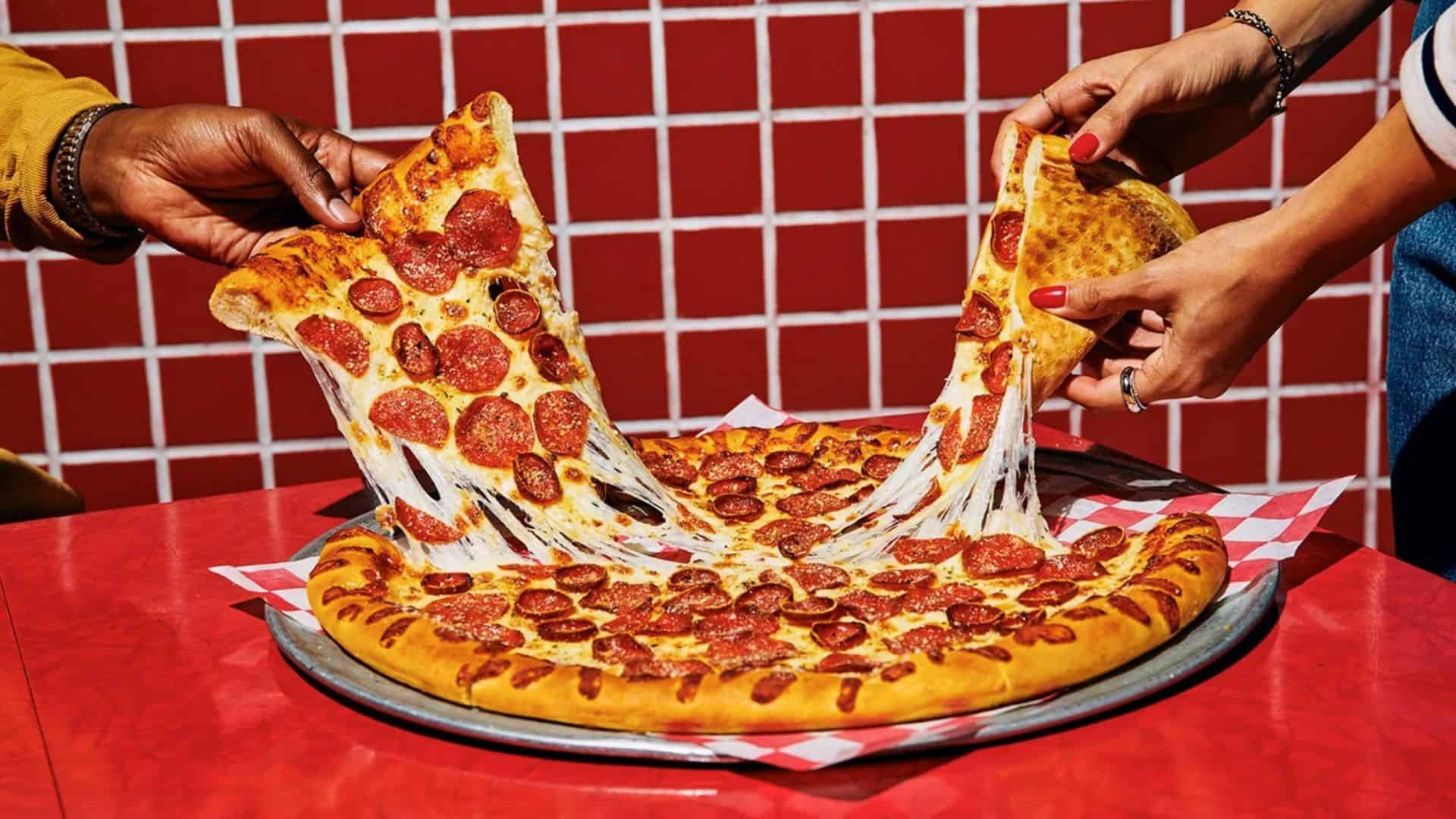 Pessoas pegando fatias de pizza do Pizza Hut