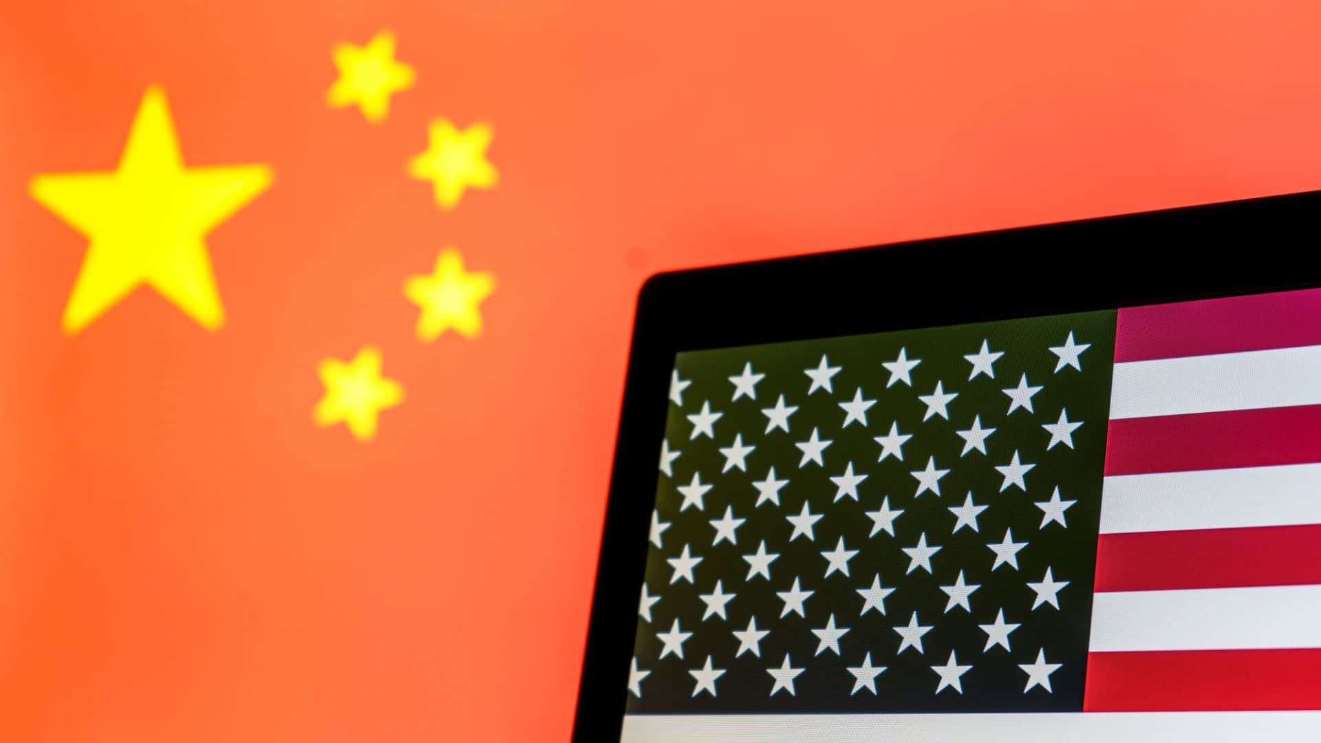 Bandeira da China ao fundo; à frente, bandeira dos EUA em tela de notebook