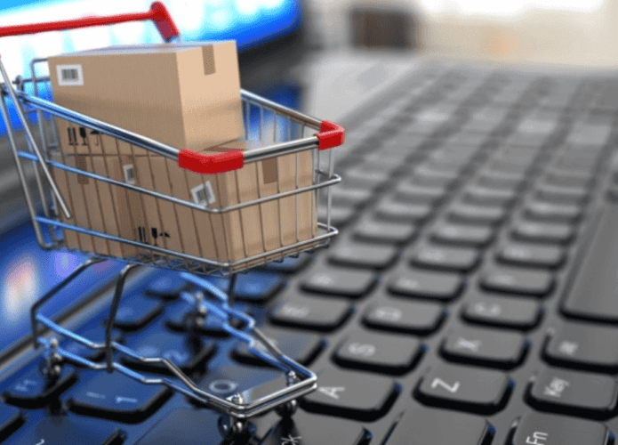 carrinho de compras com caixas dentro em cima de teclado de computador