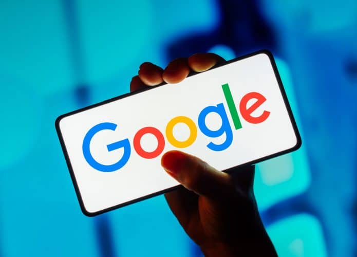 Mão segurando smartphone que está mostrando o logo do Google