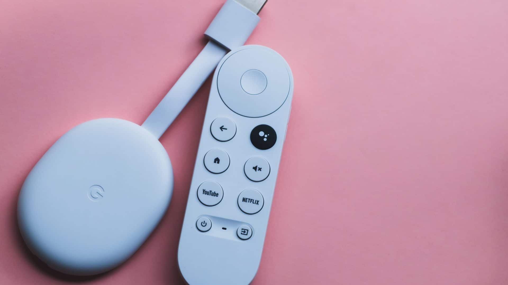 Google Chromecast com o controle remoto o ao lado em fundo rosa