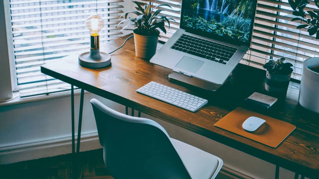 imagem mostra um home office com notebook, mouse e teclado